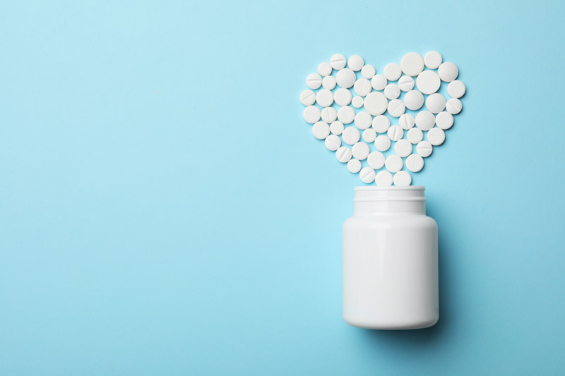 asprin pills in the shape of a heart on a blue background