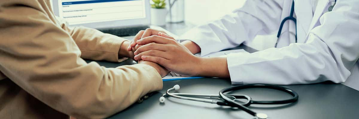 doctor holding patients hands in a reassuring manner